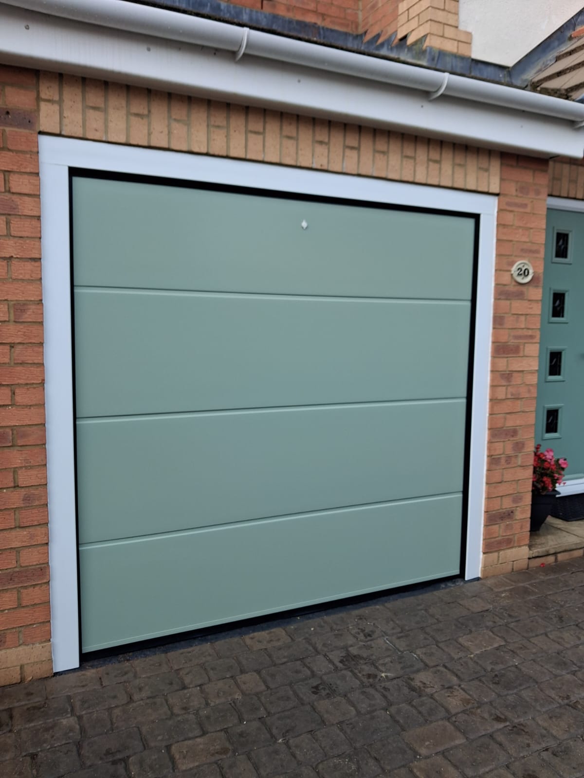 Green insulated sectional garage door with white frame, Daventry