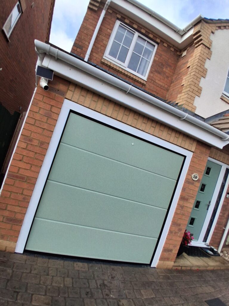 Motor-operated green sectional garage door on a Daventry home